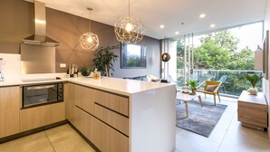 Una cocina moderna con horno empotrado, armarios de madera e iluminación colgante.