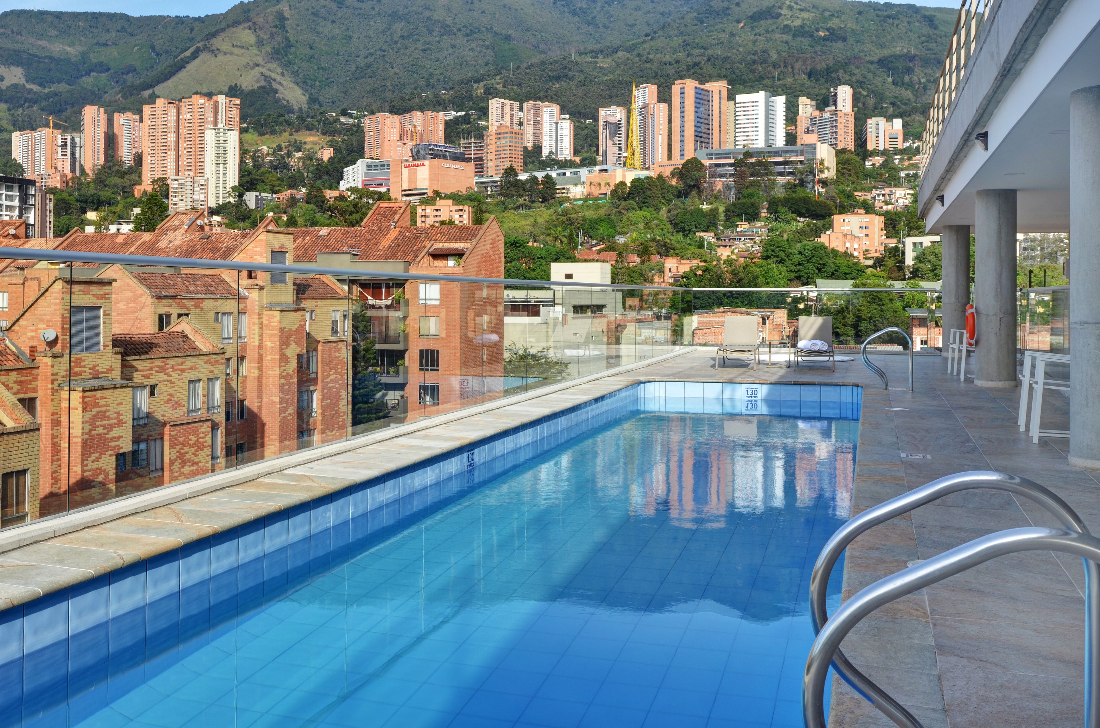A swimming pool with a view of high-rise buildings and hills in the background.