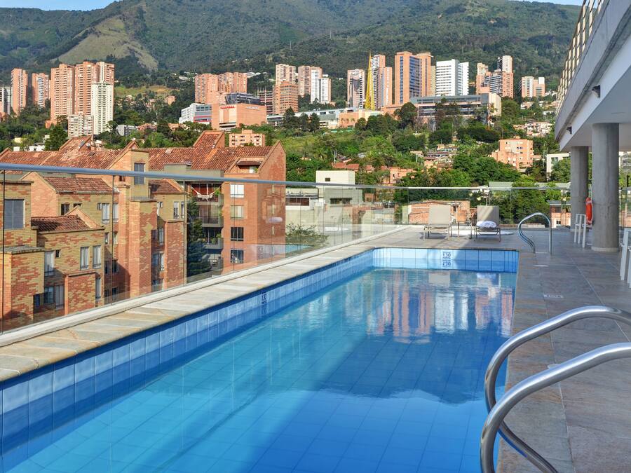A swimming pool with a view of high-rise buildings and hills in the background.