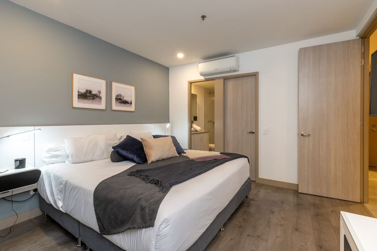 A modern bedroom with a large bed, bedside table, and a wardrobe.