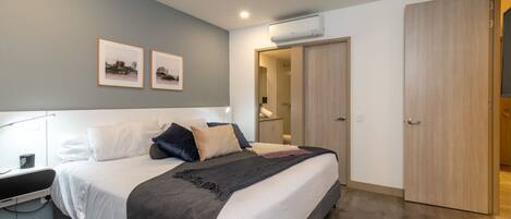 A modern bedroom with a large bed, bedside table, and a wardrobe.