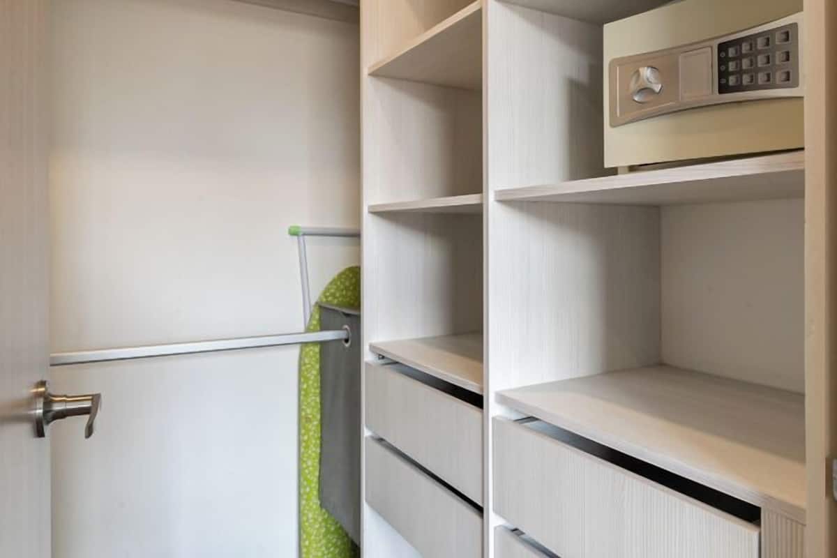 A walk-in closet with multiple shelves and a built-in safe.
