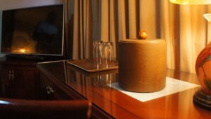 Habitación de hotel con televisión de pantalla plana, minibar, lámpara y un globo decorativo.