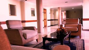 Vestíbulo de hotel con zona de estar que incluye sillones y una mesa de centro con un arreglo floral.