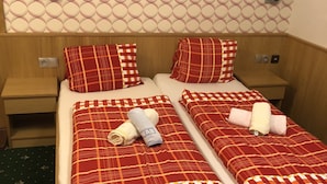Un lit double avec une couette à carreaux rouges et blancs, deux oreillers et des serviettes.