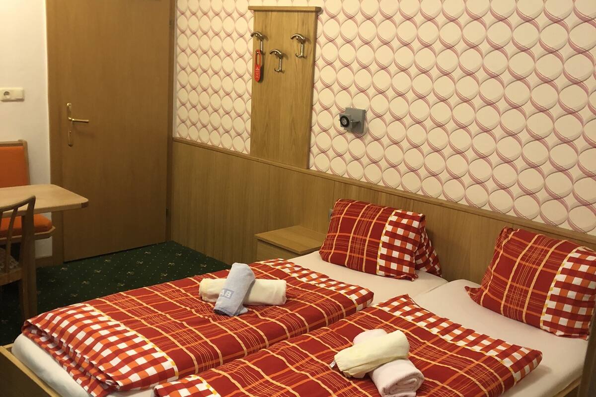 A hotel room with a bed, a desk, and a door.