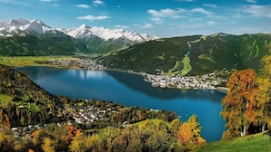 Une vue panoramique d’une région montagneuse, avec un lac, une petite ville et, au loin, des sommets enneigés.