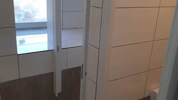 A corridor with tiled walls and a window leading to an outdoor area.