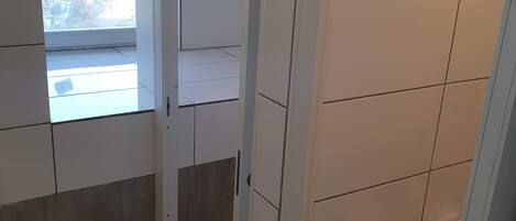 A corridor with tiled walls and a window leading to an outdoor area.