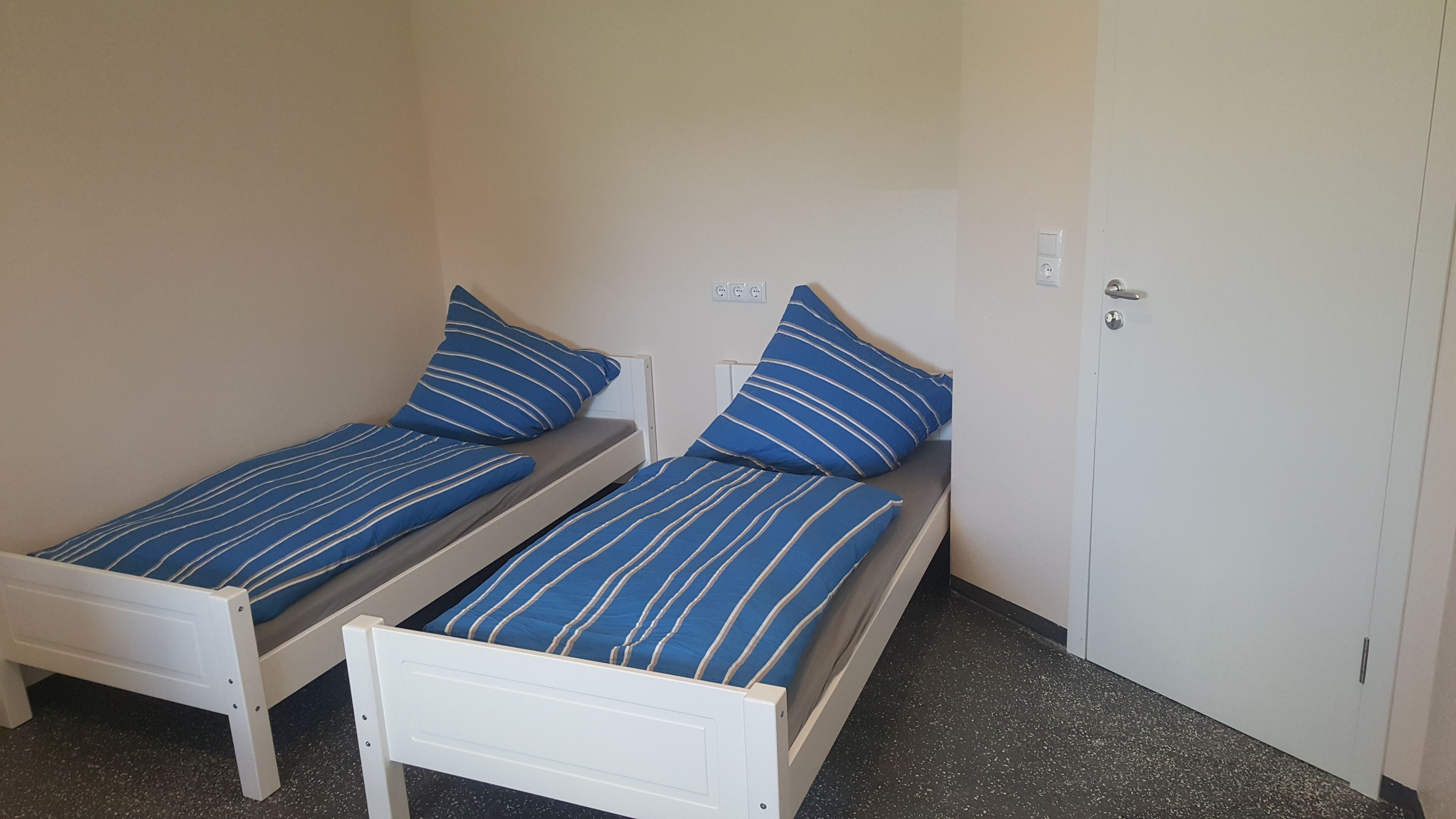 A small room with two single beds, each with blue-striped bedding.