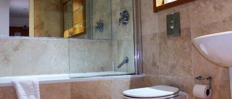A modern bathroom with a glass shower enclosure, a white toilet, and a sink with a mirror above it.
