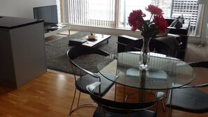 A modern living room with a glass dining table, black chairs, a sofa, and a coffee table.