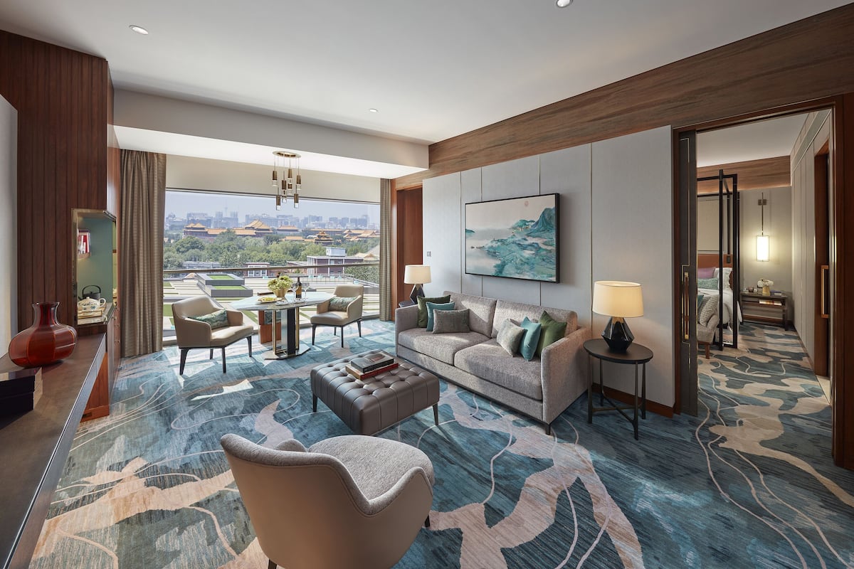 Une chambre d’hôtel spacieuse dotée d’une grande fenêtre donnant sur la ville, d’un canapé confortable, d’un coin repas et d’un design moderne.