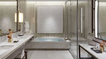 A modern bathroom with a large bathtub, two sinks, and a glass shower enclosure.