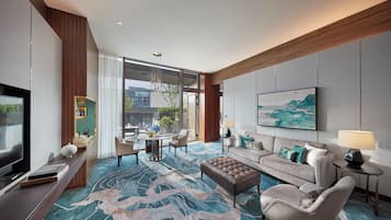 A modern hotel room with a large TV, comfortable seating, a dining area, and a view of the outdoors.