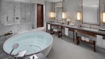 A modern bathroom with a large oval bathtub, a glass-enclosed shower, and a vanity with two sinks and a mirror.