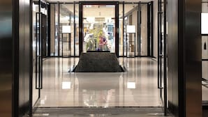 Una entrada de hotel moderna con piso reflectante, un abanico decorativo y un arreglo floral central.