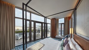 Amplia habitación de hotel con una cama grande, vista a la terraza exterior y un diseño interior moderno.