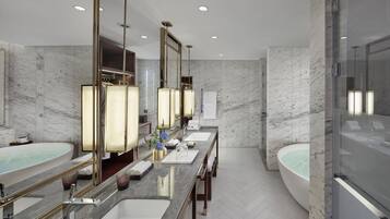 A modern bathroom with two sinks, a large mirror, and a separate bathtub.