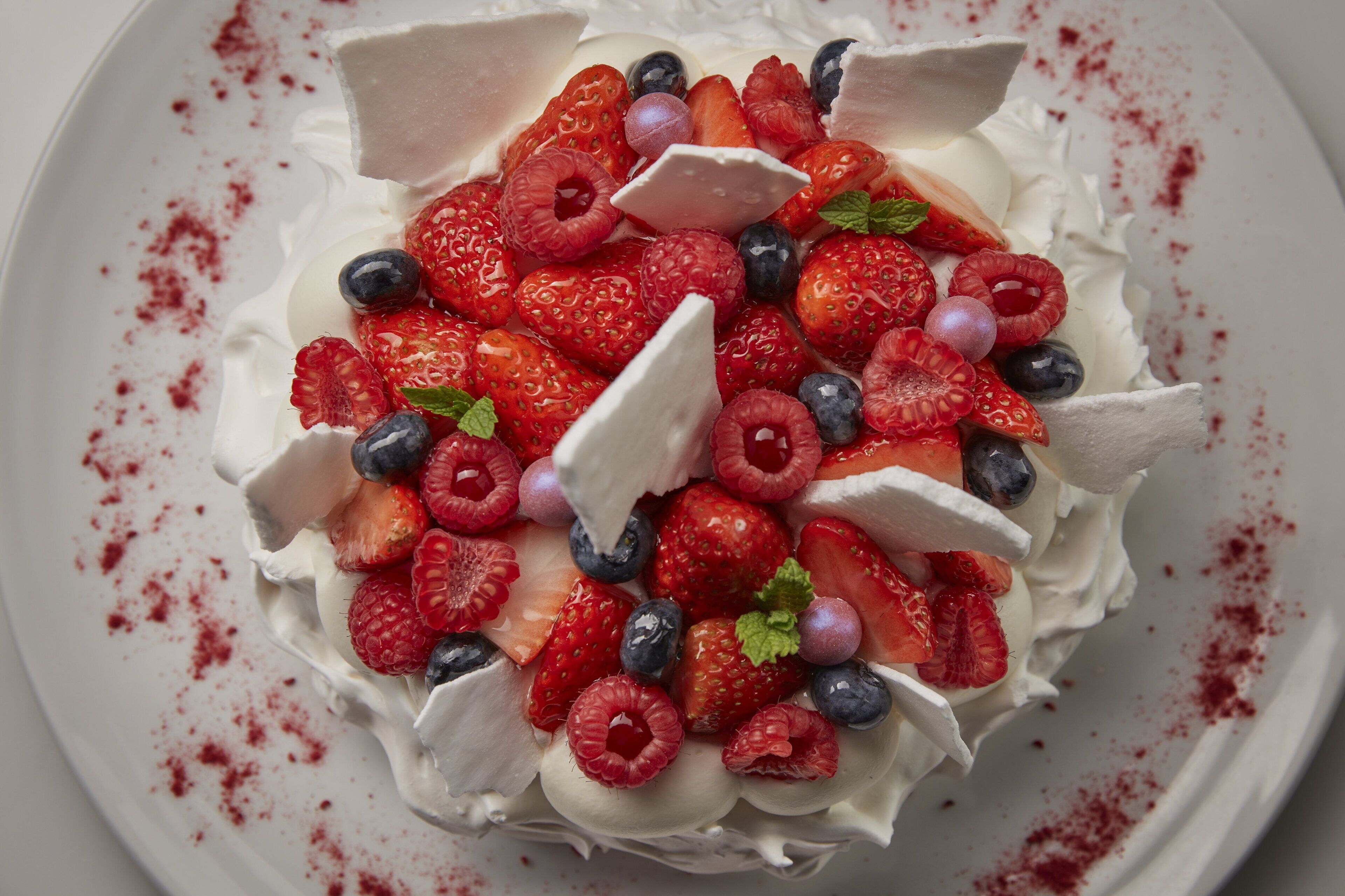 A dessert with whipped cream, strawberries, raspberries, and blueberries.