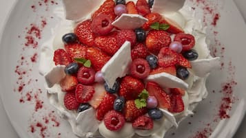A dessert with whipped cream, strawberries, raspberries, and blueberries.