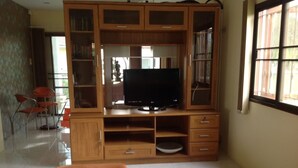 Una sala de estar con un mueble de madera para entretenimiento, un televisor de pantalla plana y un sofá.