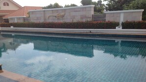Una piscina con agua cristalina azul, rodeada por una solana con baldosas y un muro bajo con diseño decorativo.