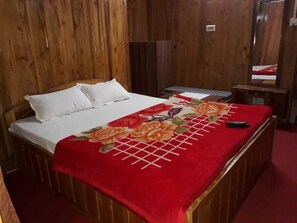 A wooden bed with white pillows and a red floral bedspread. - The Park Hotel (Kurseong)