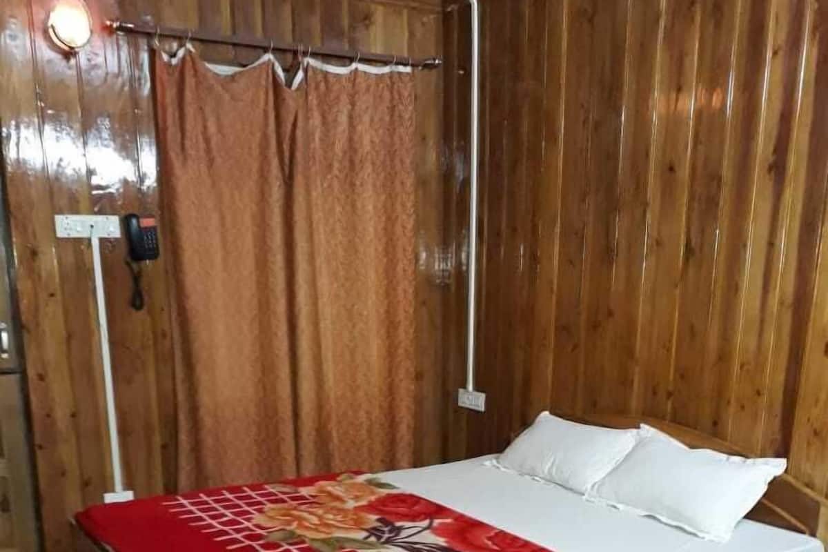Una habitación de madera con una cama, una mesita de noche y un teléfono.