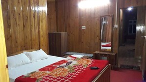 A wooden room with a bed, a desk, and a mirror. - The Park Hotel (Kurseong)