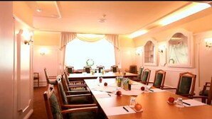 Une salle de conférence avec une longue table, des chaises et une grande fenêtre.