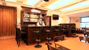 Un espace bar avec un barman, des tabourets de bar et une étagère remplie de bouteilles.