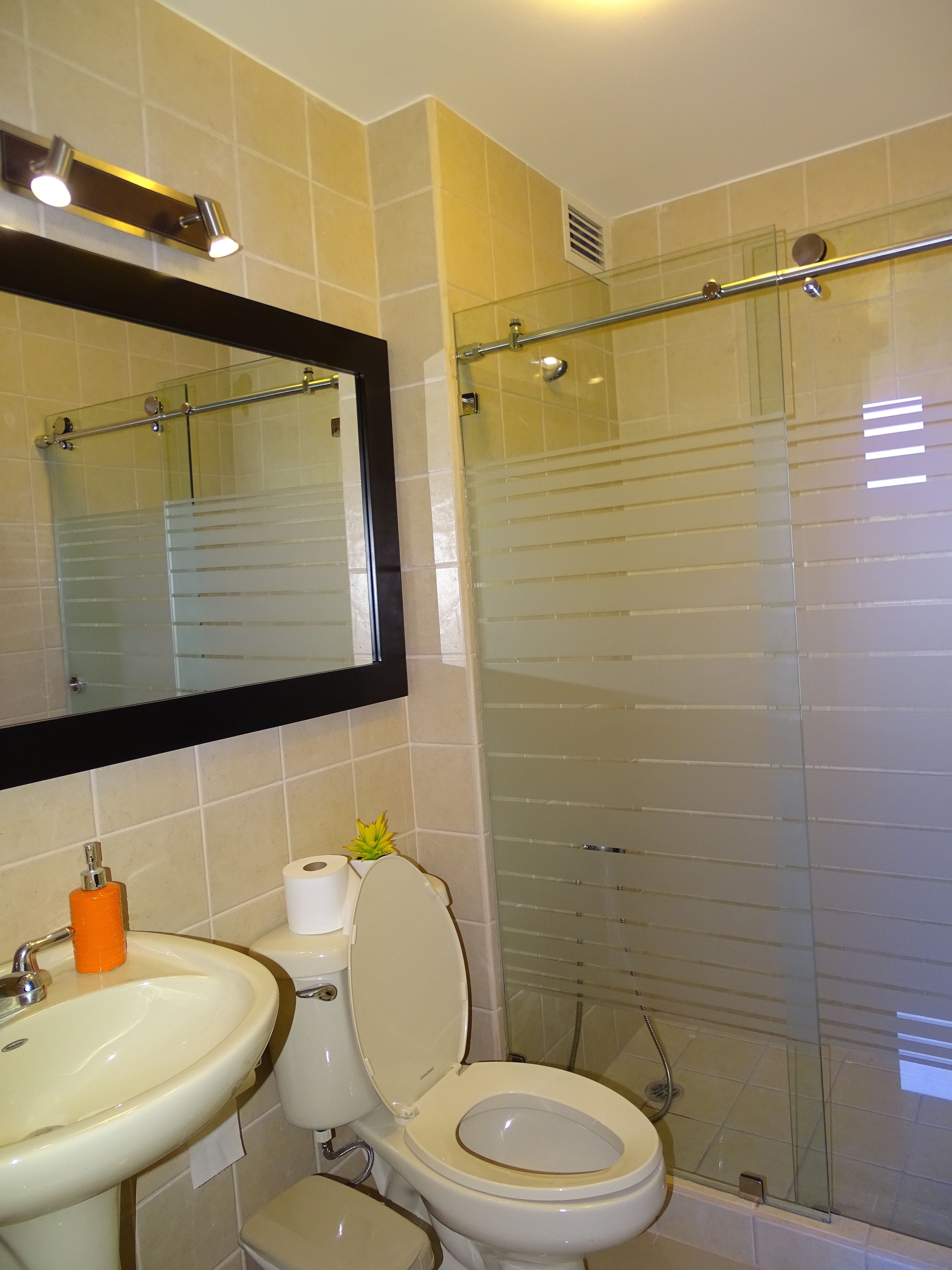 Un baño con lavamanos, inodoro y cabina de ducha de vidrio.