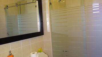 Un baño con lavamanos, inodoro y cabina de ducha de vidrio.
