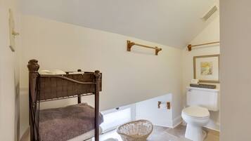A bedroom with a wooden bed, a wicker basket, a white toilet, and a framed picture on the wall.