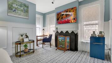 A room with a fireplace, a blue cabinet, a television, and artwork on the walls.