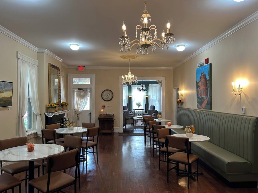 A hotel dining area with chandeliers, round tables, and a green booth.