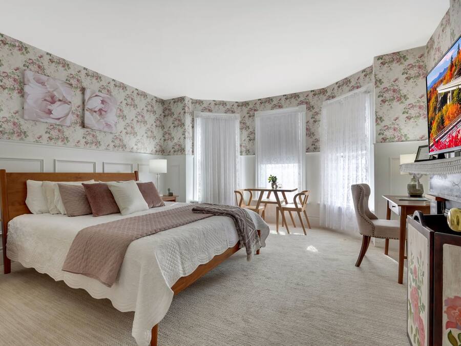 A bedroom with a large bed, a desk, and a television.