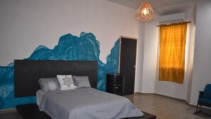 A bedroom with a bed, a nightstand, a wall mural, a window with curtains, and a chair. - Hotel el Sole - Hostel (Santa Ana)