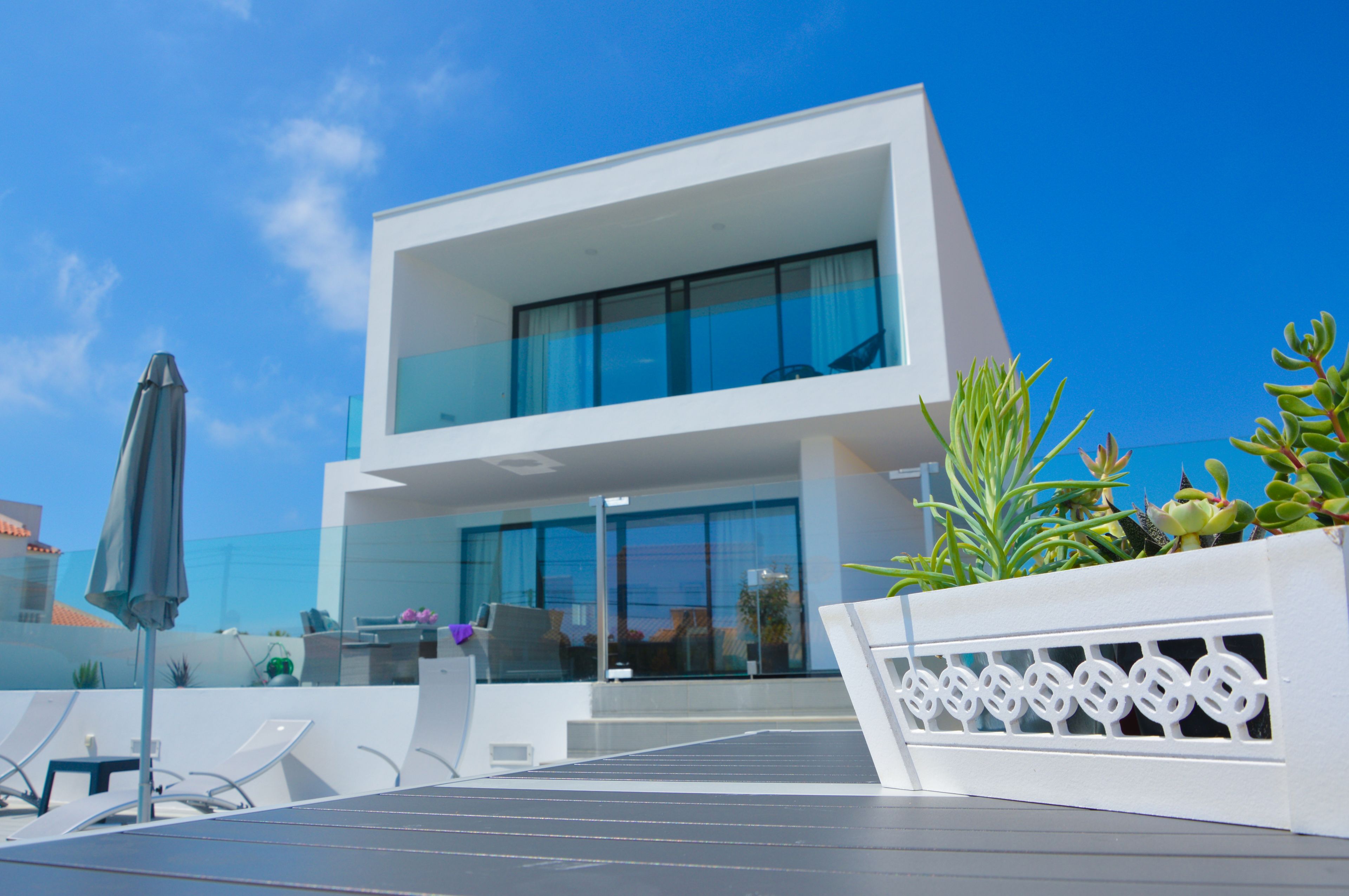 A modern two-story building with large glass windows, outdoor seating, and a solar panel array.