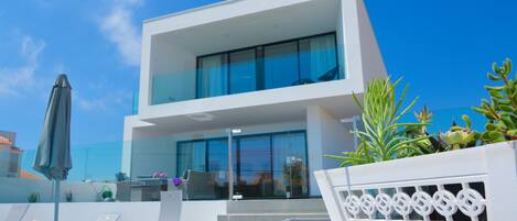 A modern two-story building with large glass windows, outdoor seating, and a solar panel array.