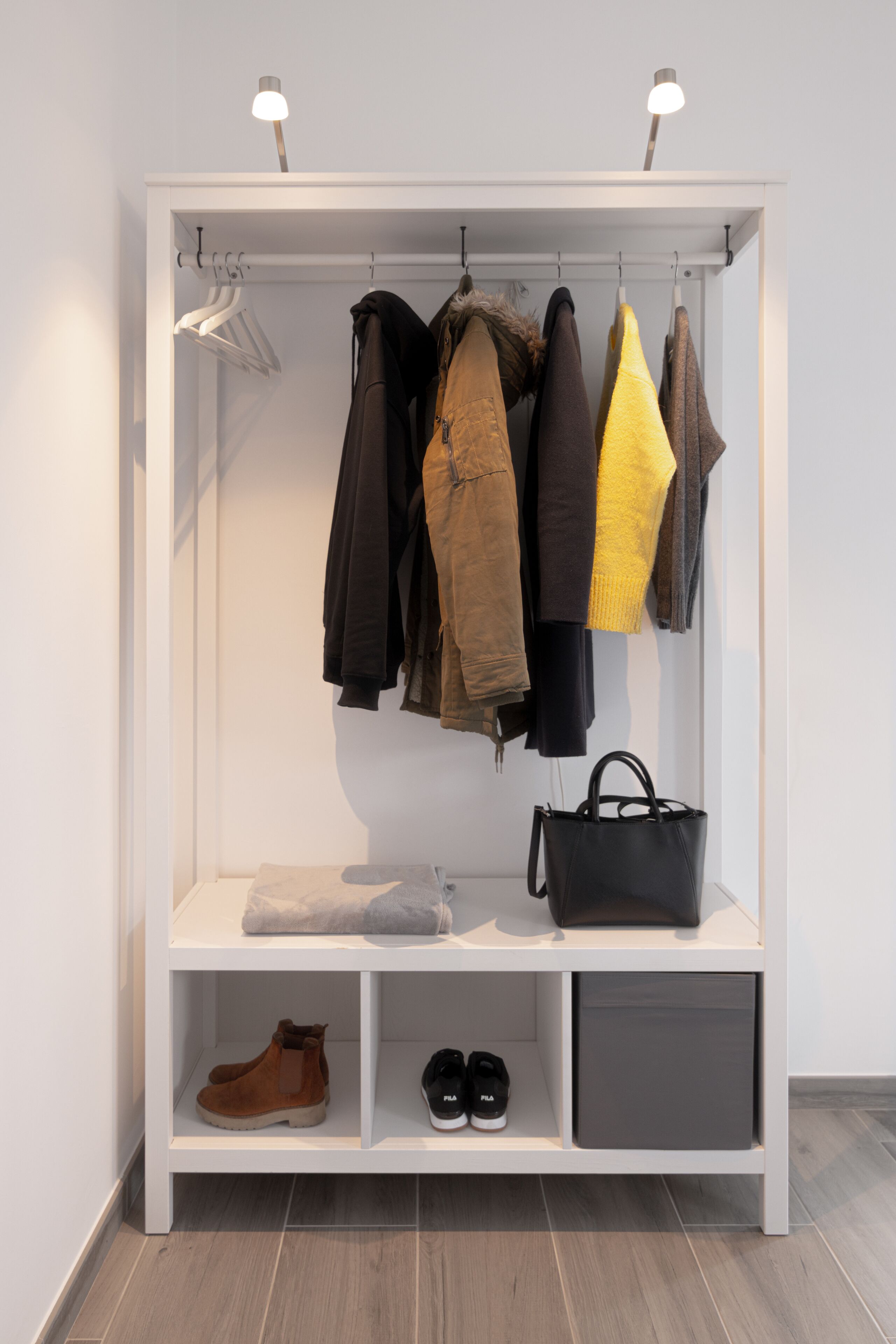 A white closet with shelves for shoes and hanging space for jackets and coats.