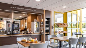 A cafe with a self-service coffee machine, seating area, and a window with a view.