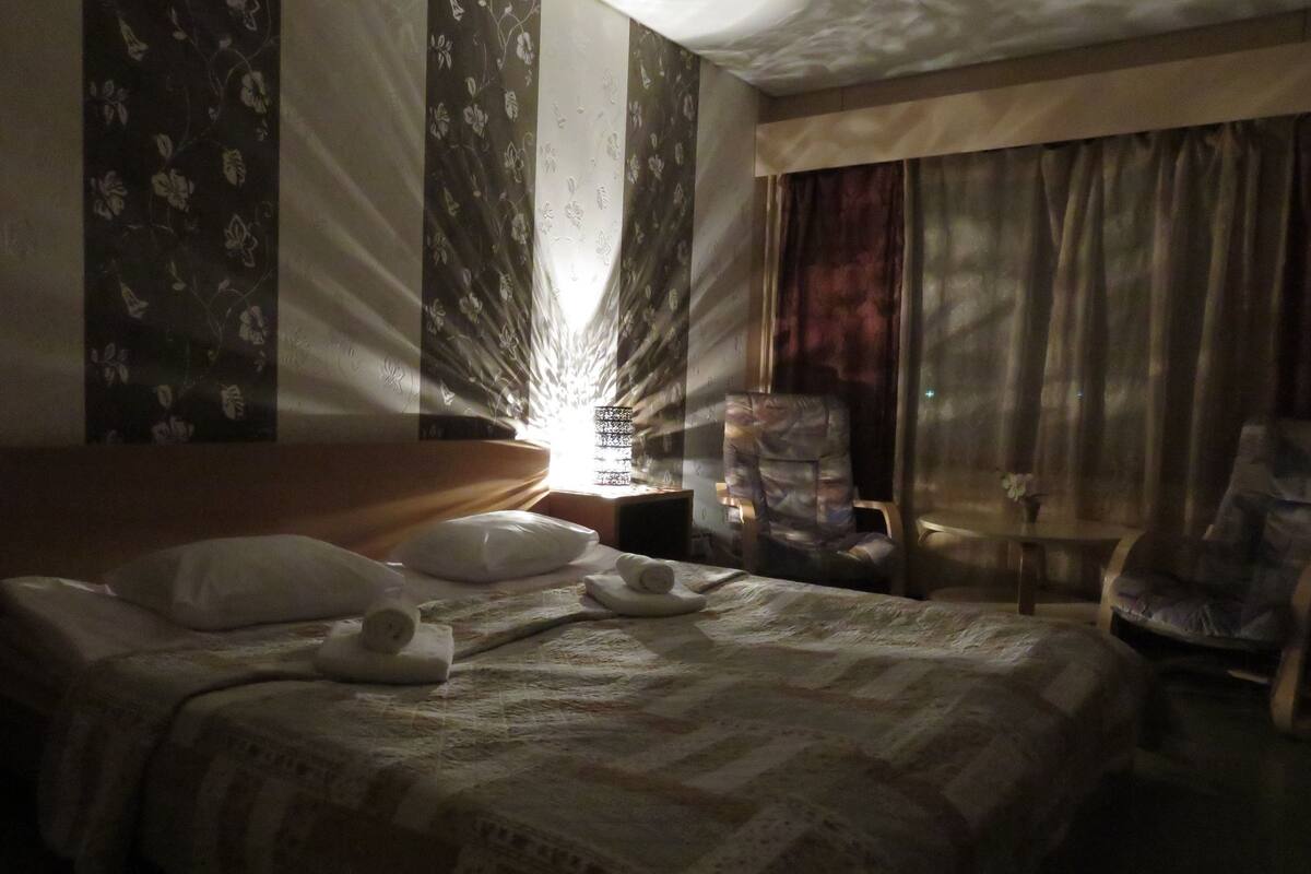 A hotel room with a bed, a chair, and a nightstand.