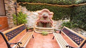 A courtyard with two wooden benches and a decorative fountain.