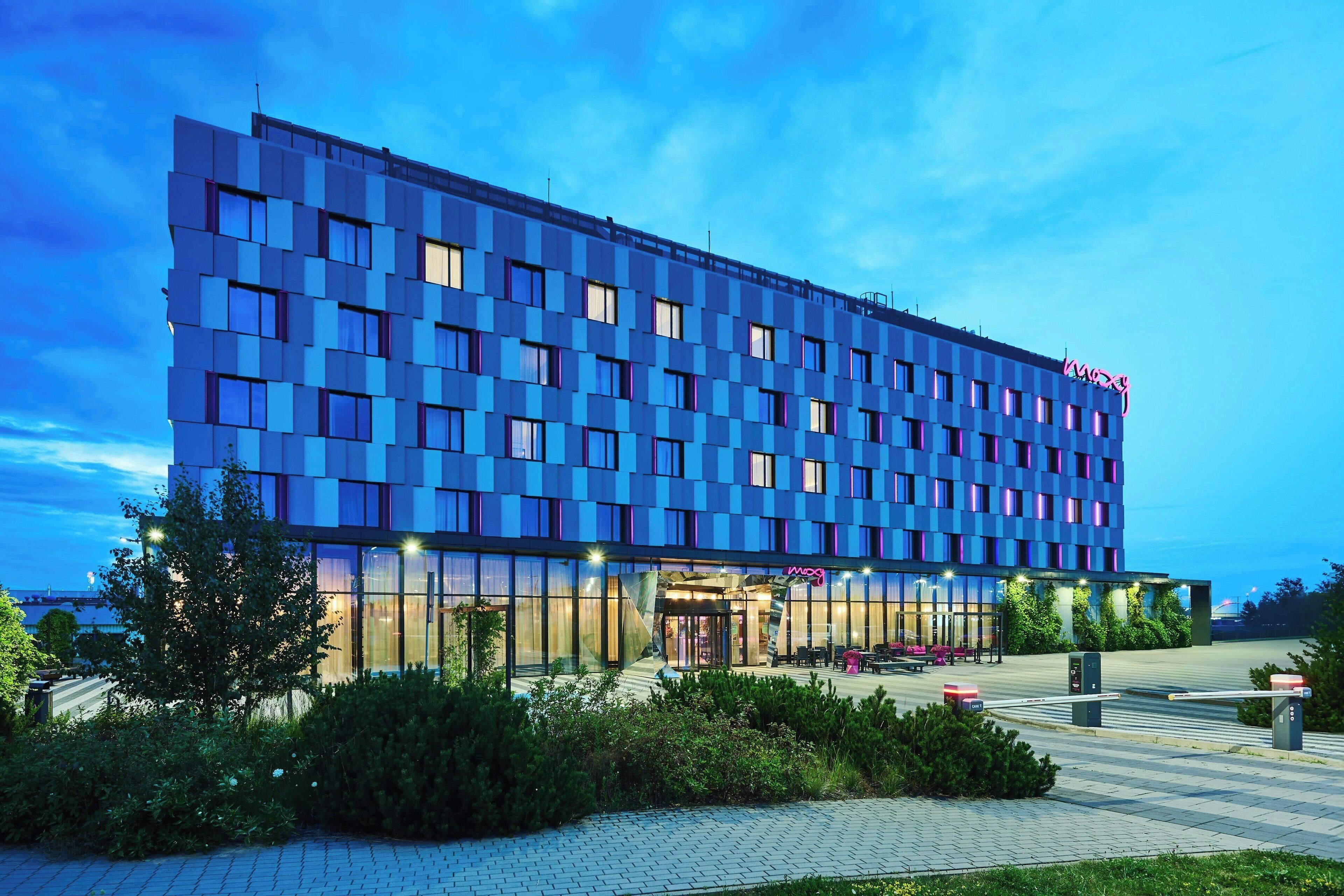 Een modern hotel met een gevel in rastervorm, grote ramen en een goed verlicht entreegebied.