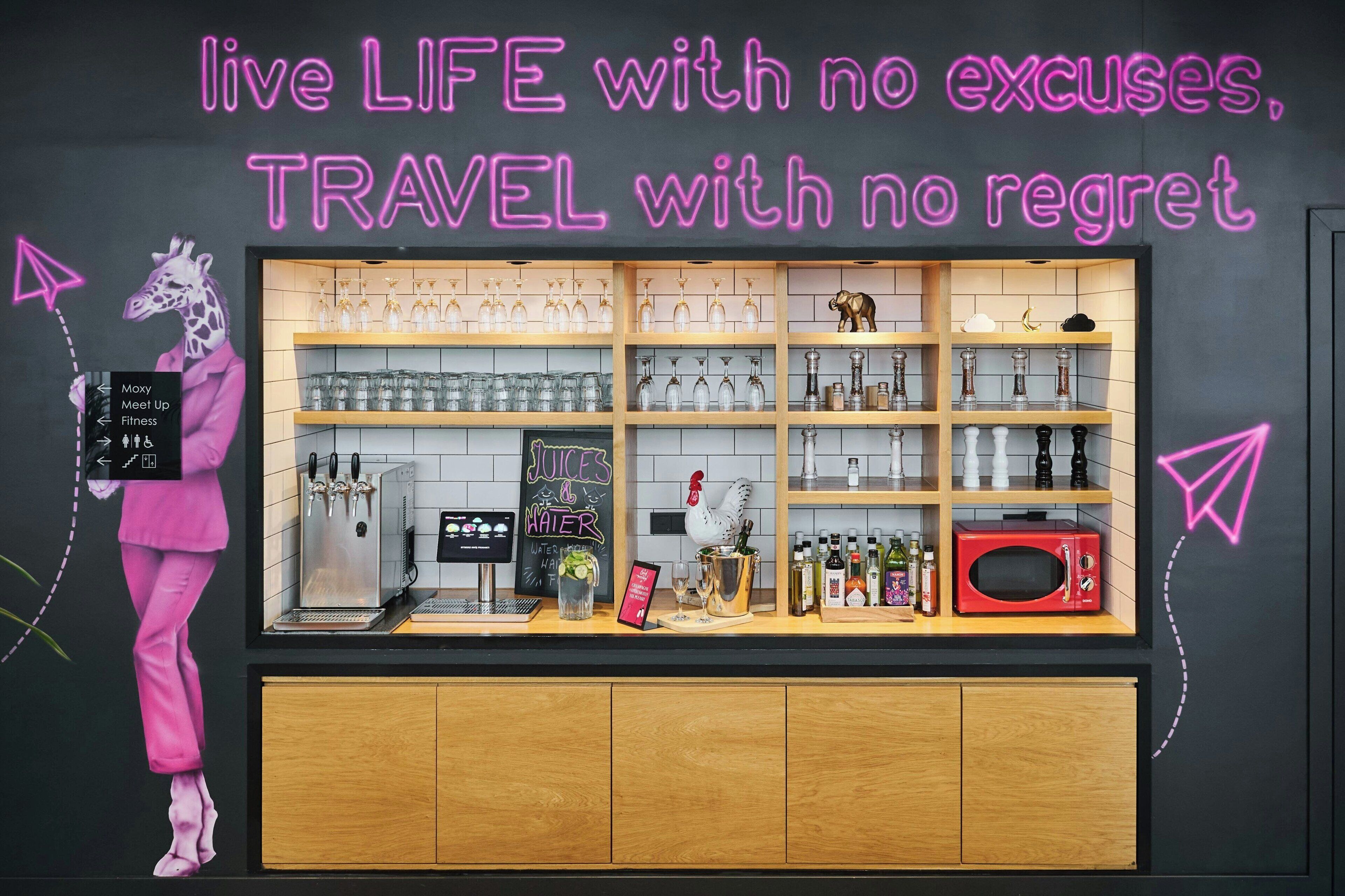 A bar area with a neon sign, shelves with bottles, a coffee machine, and a microwave.