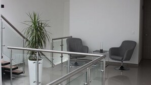 A modern interior with a staircase, two grey chairs, a potted plant, and a small table.