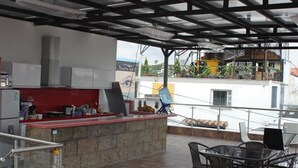 An outdoor kitchen area with a counter, chairs, and a view of the surrounding buildings.