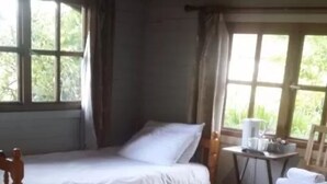 Una habitación pequeña y acogedora con una cama individual, una mesa de madera y una silla.